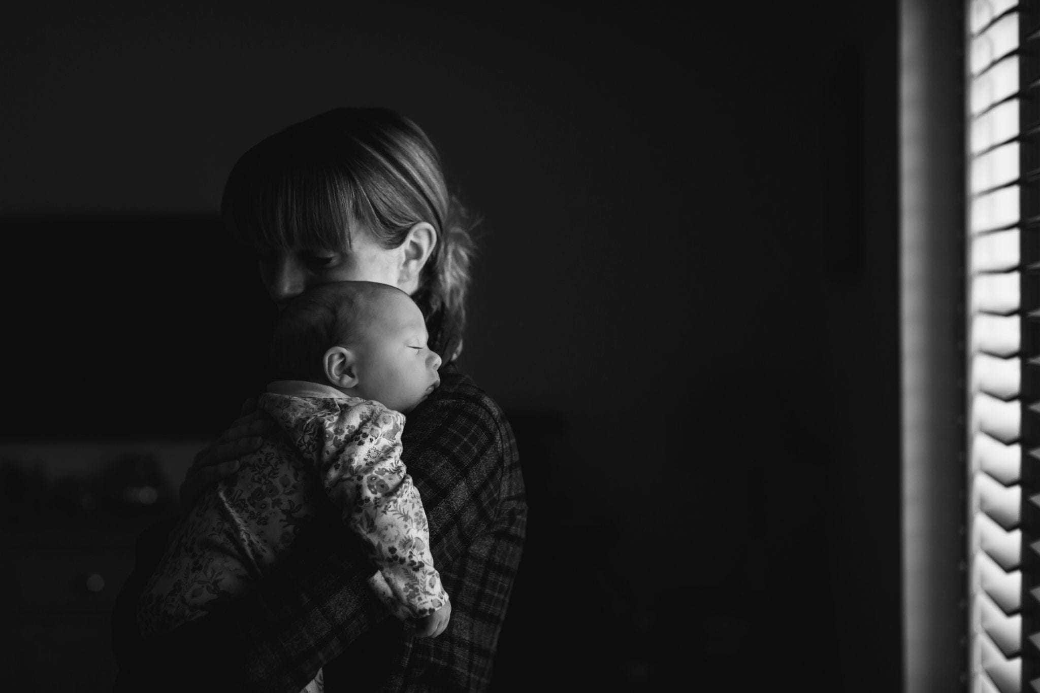 Mum and sleeping baby stand by window