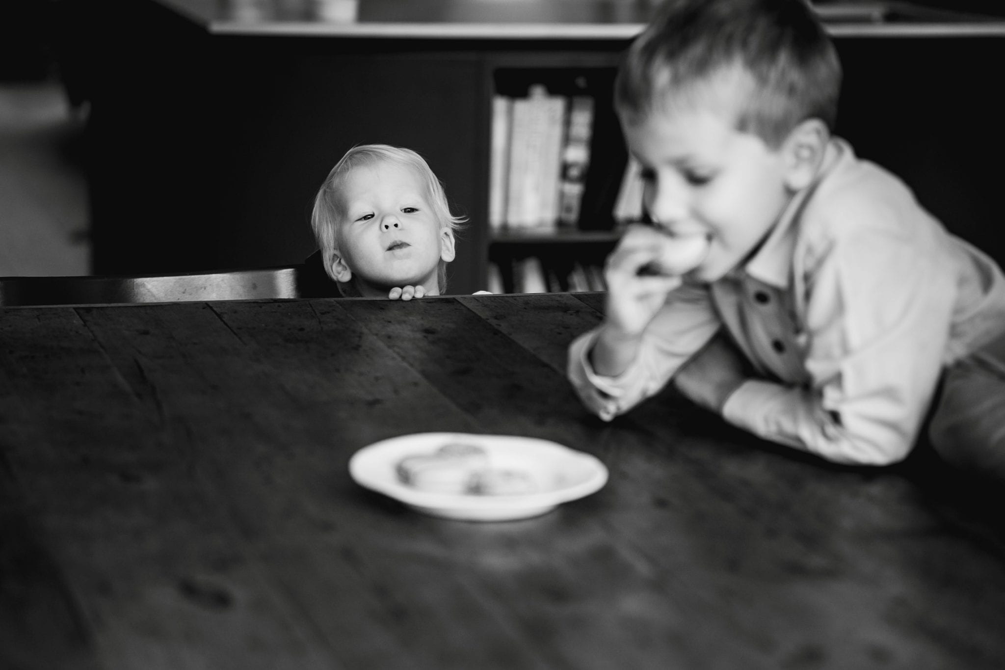 Little bot looking over the table at a biscuit