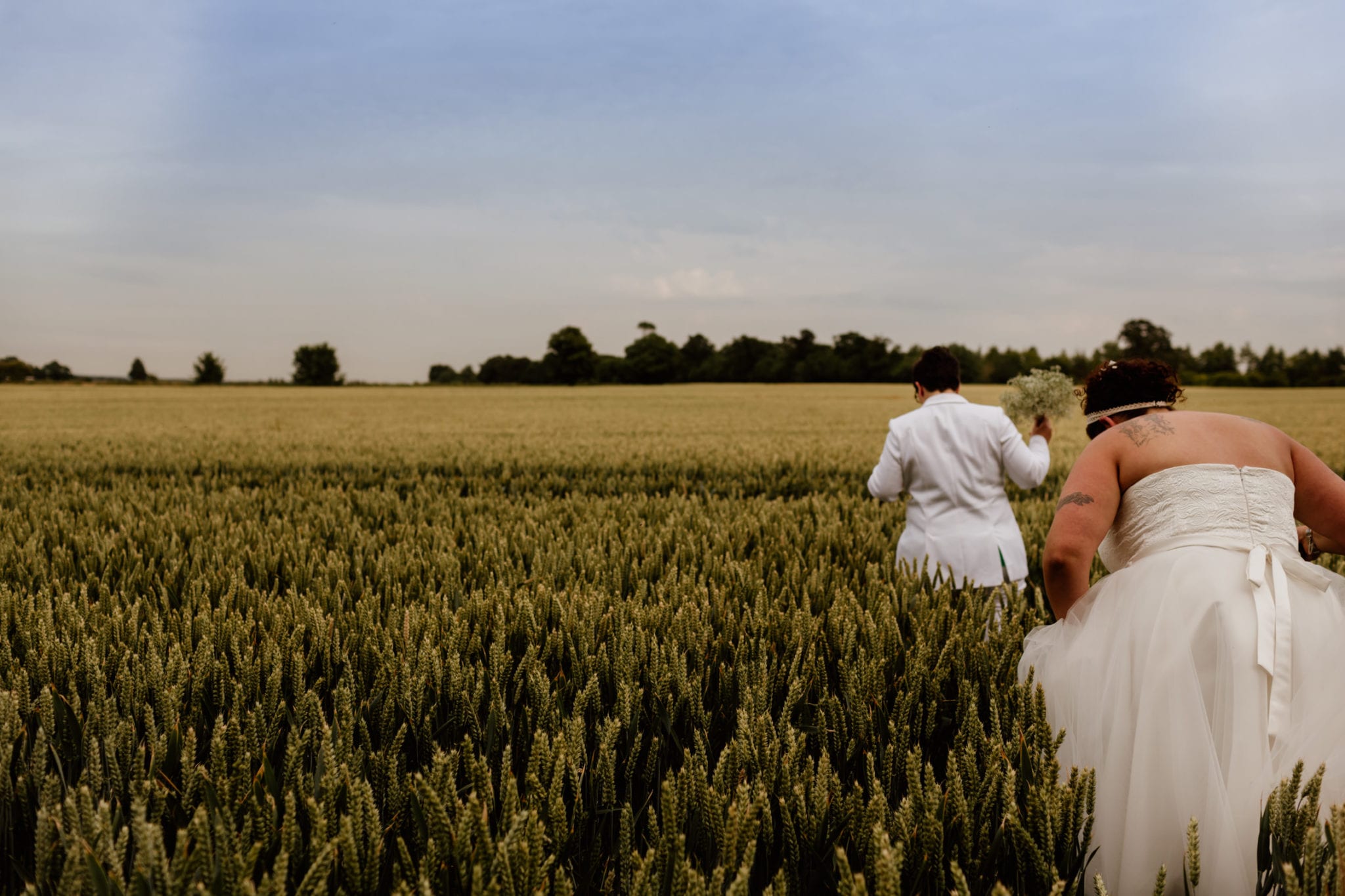 Two brides walking through corn on their wedding day
