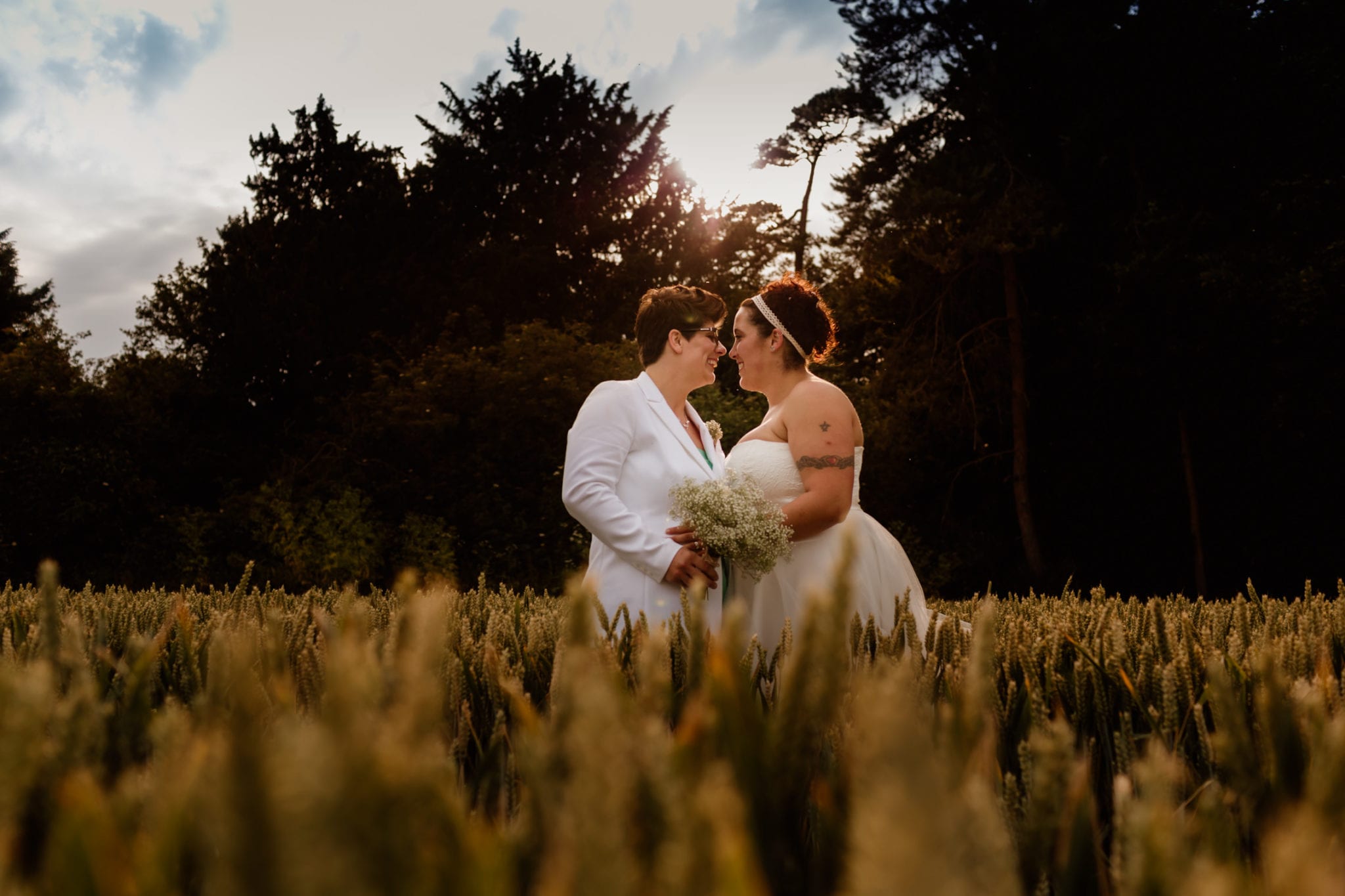 Two brides kissing on their wedding day in the sunlight