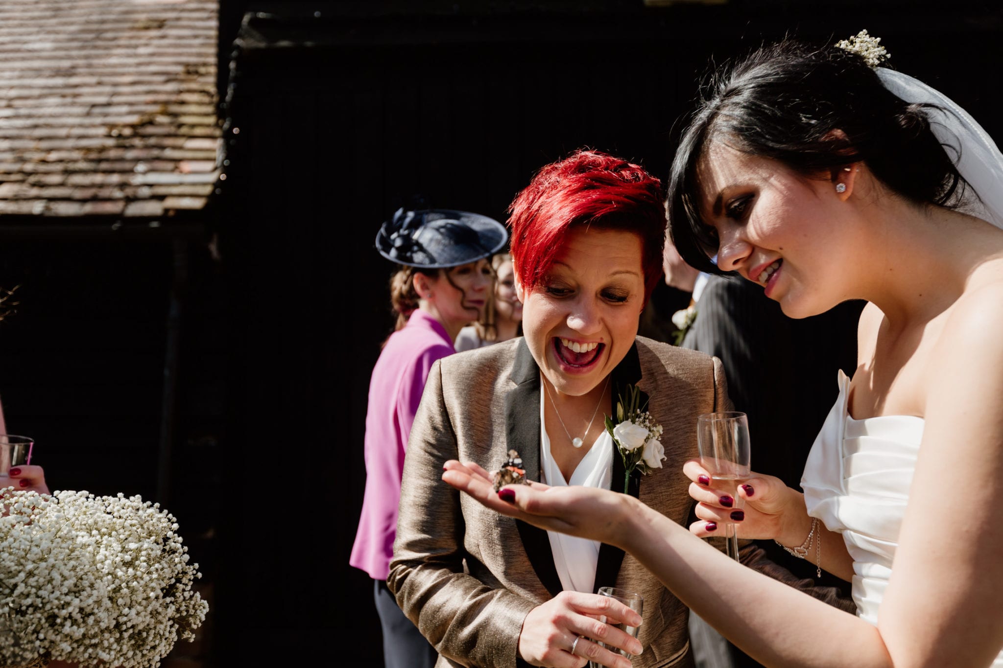 Two brides share a moment with a butterfly at wedding
