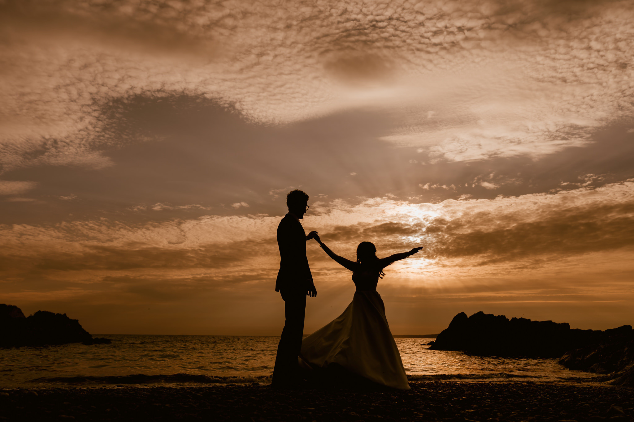 Bride and groom dancing at the beach at sunset