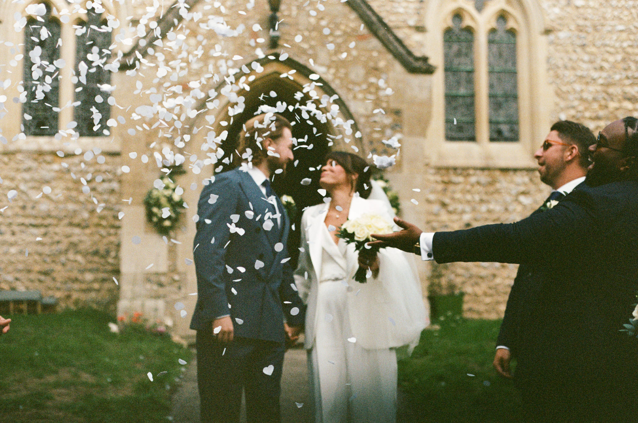 Couple exit chuech with confetti - with heavy grain. Bedfordshire Film Photographer